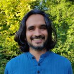 Headshot of Murad standing in front of vibrant trees.
