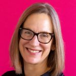 headshot of smiling Pam Franks with a bright pink background